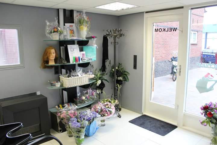 De ingang van de salon met planten en bloemen bij de deur